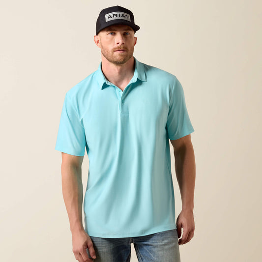 Man wearing a light blue polo shirt and black cap with 'Ariat' logo on a beige background