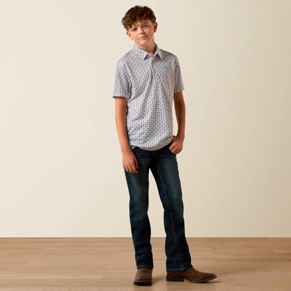 Young boy wearing a checkered shirt and jeans standing against a plain background
