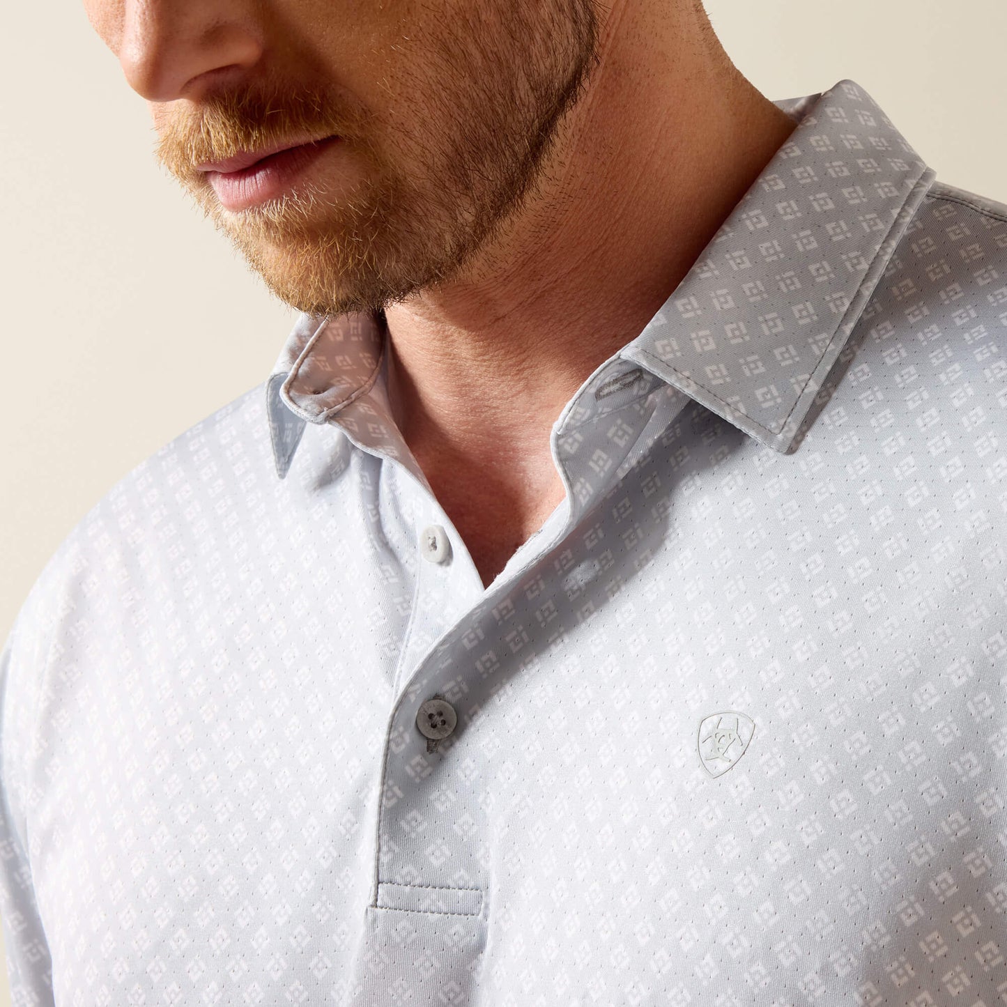Man wearing a light gray patterned shirt with a collar, close-up of neck and chest.