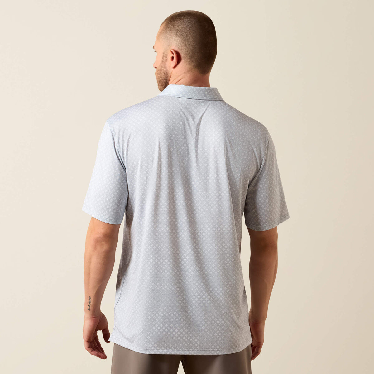 Man wearing a gray polo shirt against a beige background