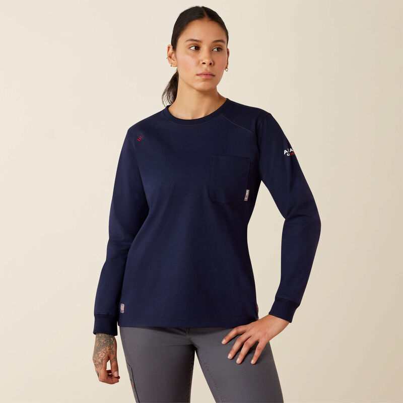 A woman modeling a navy blue long-sleeve crewneck top with a chest pocket, paired with gray leggings, against a plain beige background.