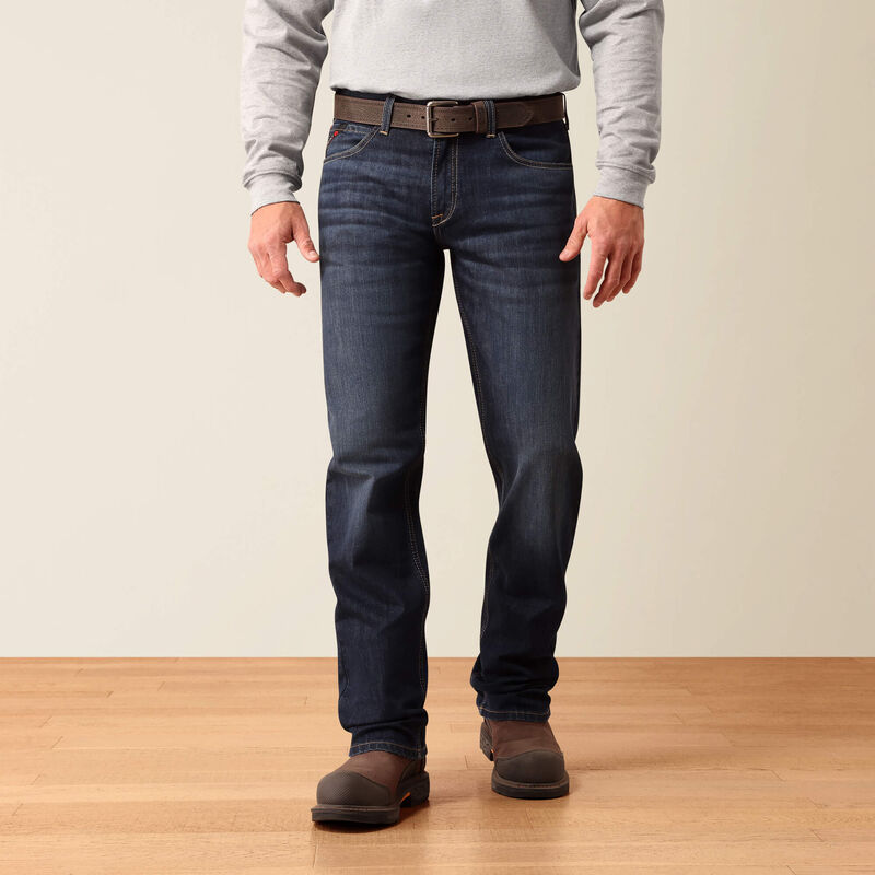 Close-up of a person wearing dark blue denim jeans, showing the back pocket with a visible Apatite brand tag and a hand pulling the waistband.