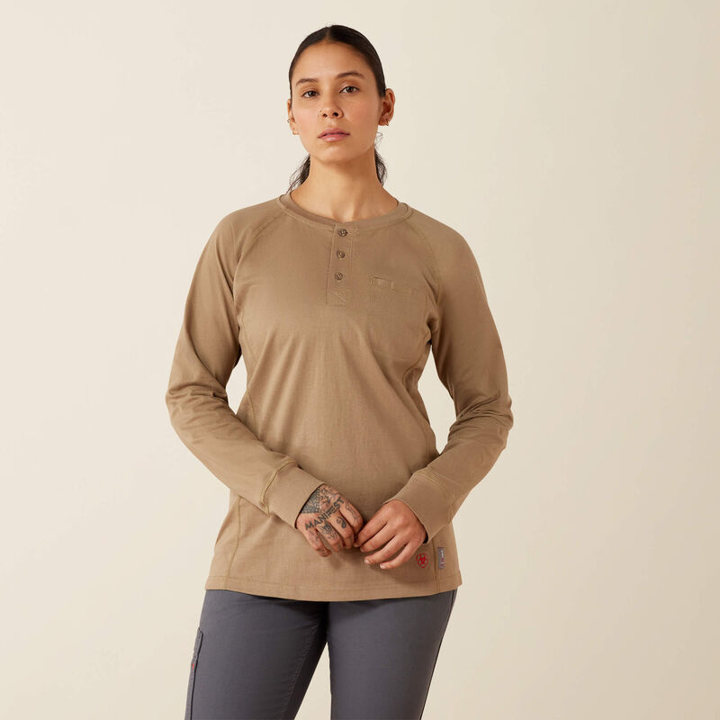 A woman modeling a tan long-sleeve henley shirt with a small chest pocket, paired with dark gray leggings, against a plain beige background.