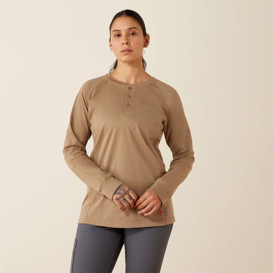 A woman modeling a tan long-sleeve henley shirt with a small chest pocket, paired with dark gray leggings, against a plain beige background.