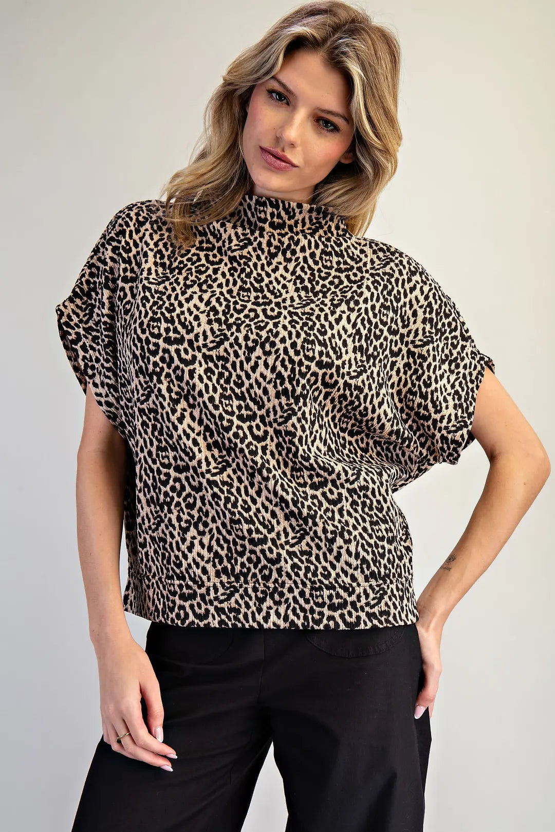 Woman wearing a leopard print top against a plain background