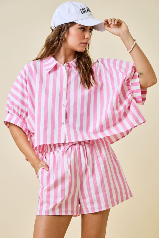 Woman wearing a pink and white striped outfit with a matching cap on a beige background