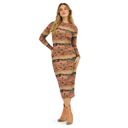 Woman wearing a fitted, long-sleeve desert landscape print midi dress with tan ankle boots.