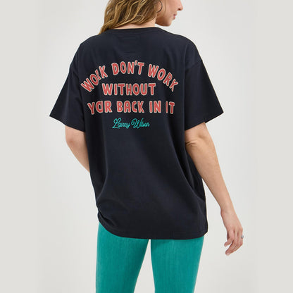 Woman wearing black graphic t-shirt with red and teal text on back, turquoise pants