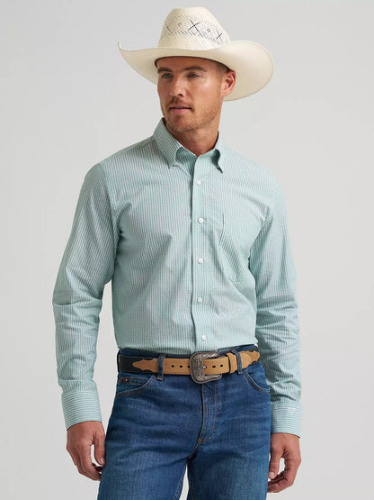 Man wearing a light blue checkered shirt, white cowboy hat, and blue jeans on a gray background