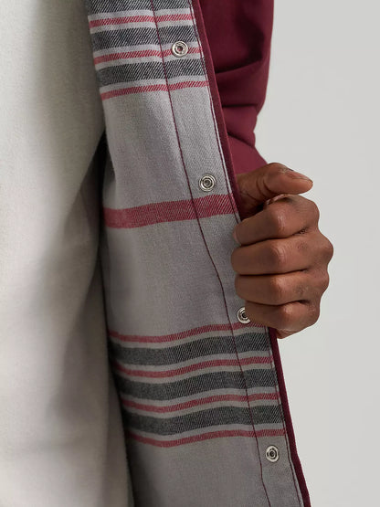 Close-up of a person wearing a gray plaid button-up shirt with red and black stripes, holding the open front to reveal a burgundy inner layer or lining.