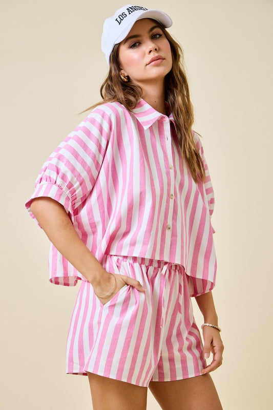 Woman wearing a pink and white striped outfit with a cap on a beige background