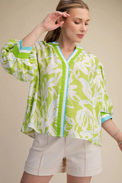 Woman wearing a green and white leaf-patterned kimono-style jacket against a beige background