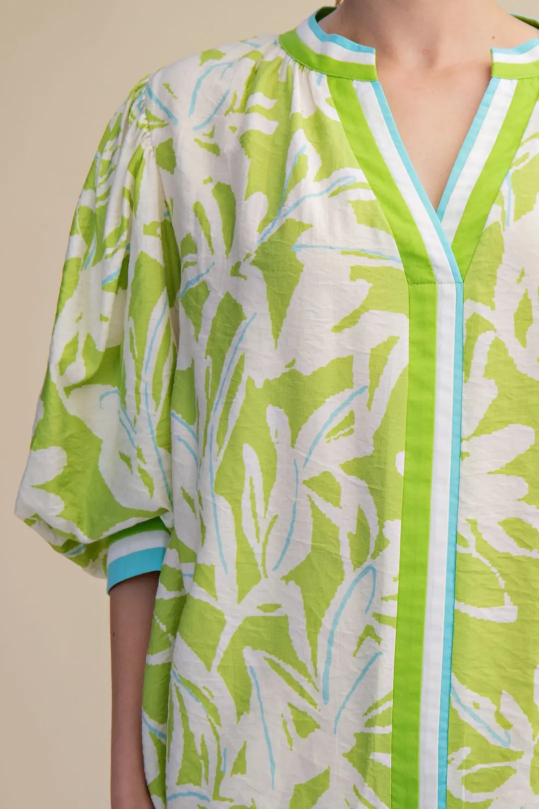 Green and white floral patterned cover-up on a beige background