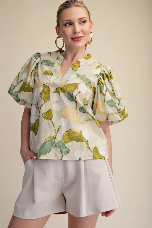 Woman wearing a floral blouse and beige shorts against a beige background