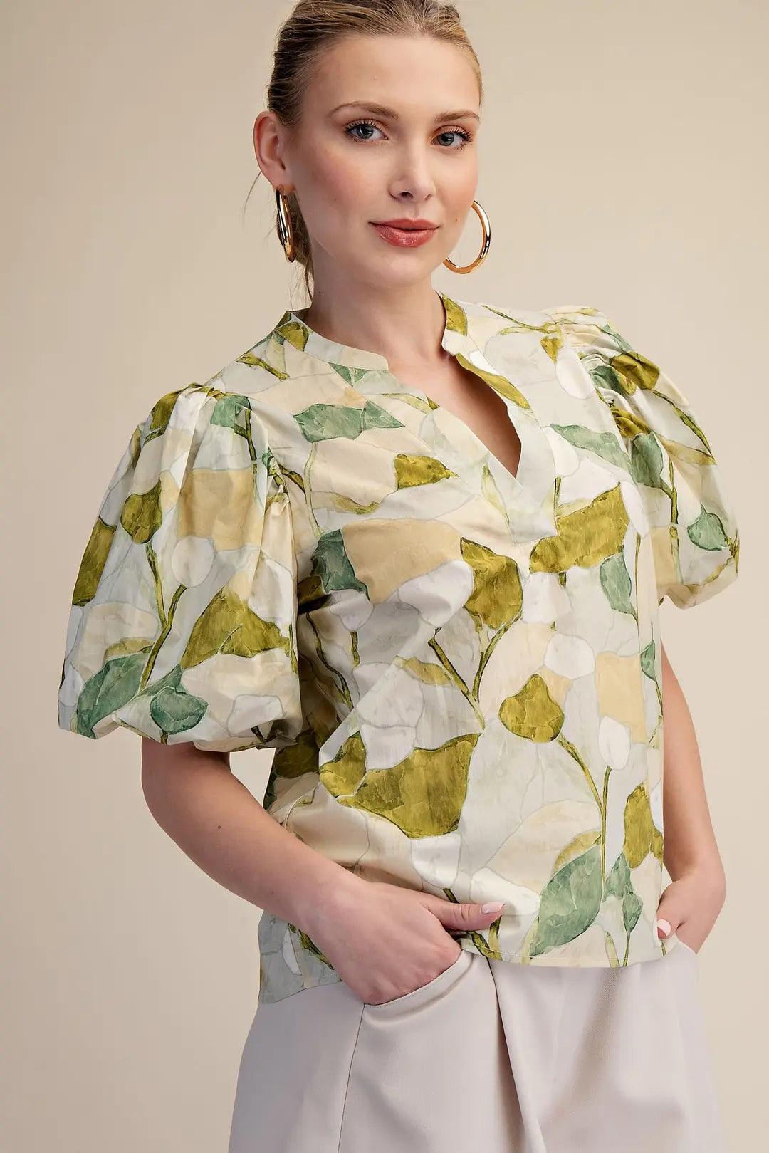 Woman wearing a floral blouse with puff sleeves against a beige background