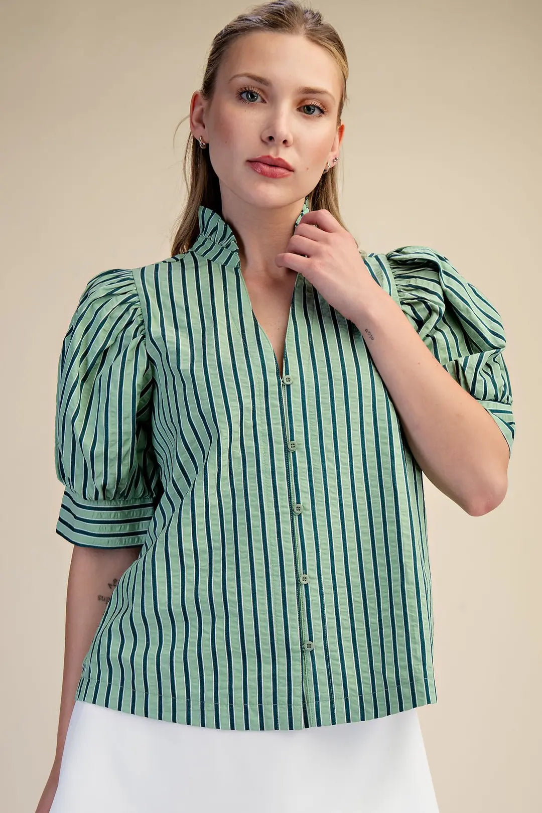 Woman wearing a green and white striped shirt against a beige background