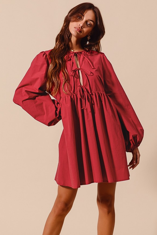 Woman wearing a red dress with long sleeves on a beige background