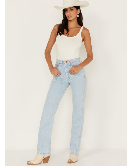 Woman in white tank top, light wash straight-leg jeans, cowboy hat, and boots