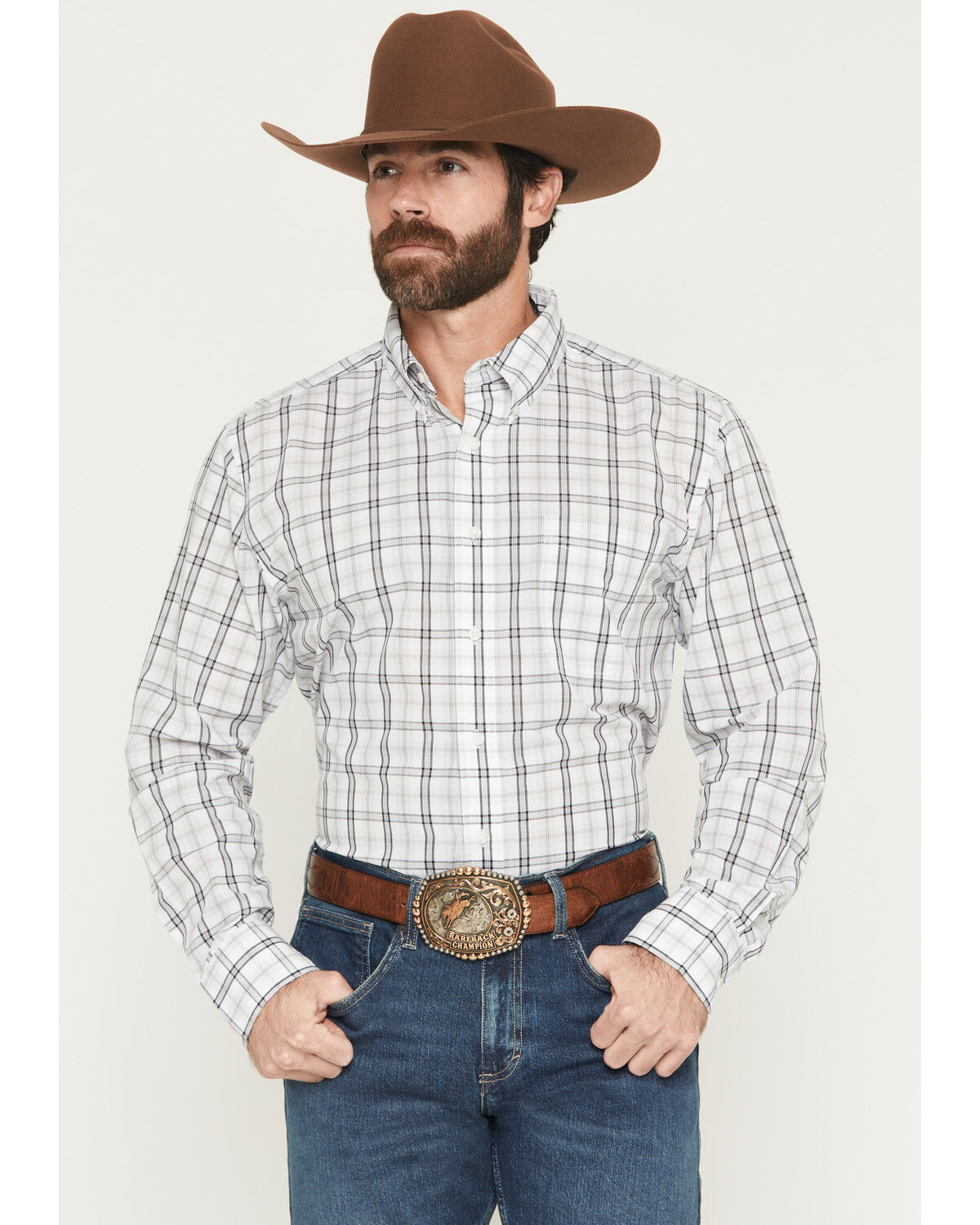 Man in plaid western shirt, cowboy hat, jeans, and decorative belt buckle