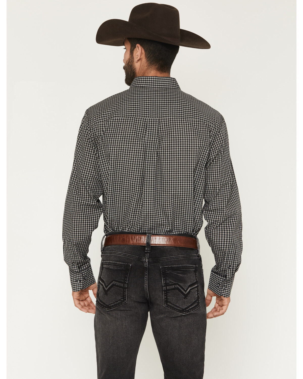 Man wearing checkered western shirt, black jeans, brown belt, and cowboy hat, shown from back