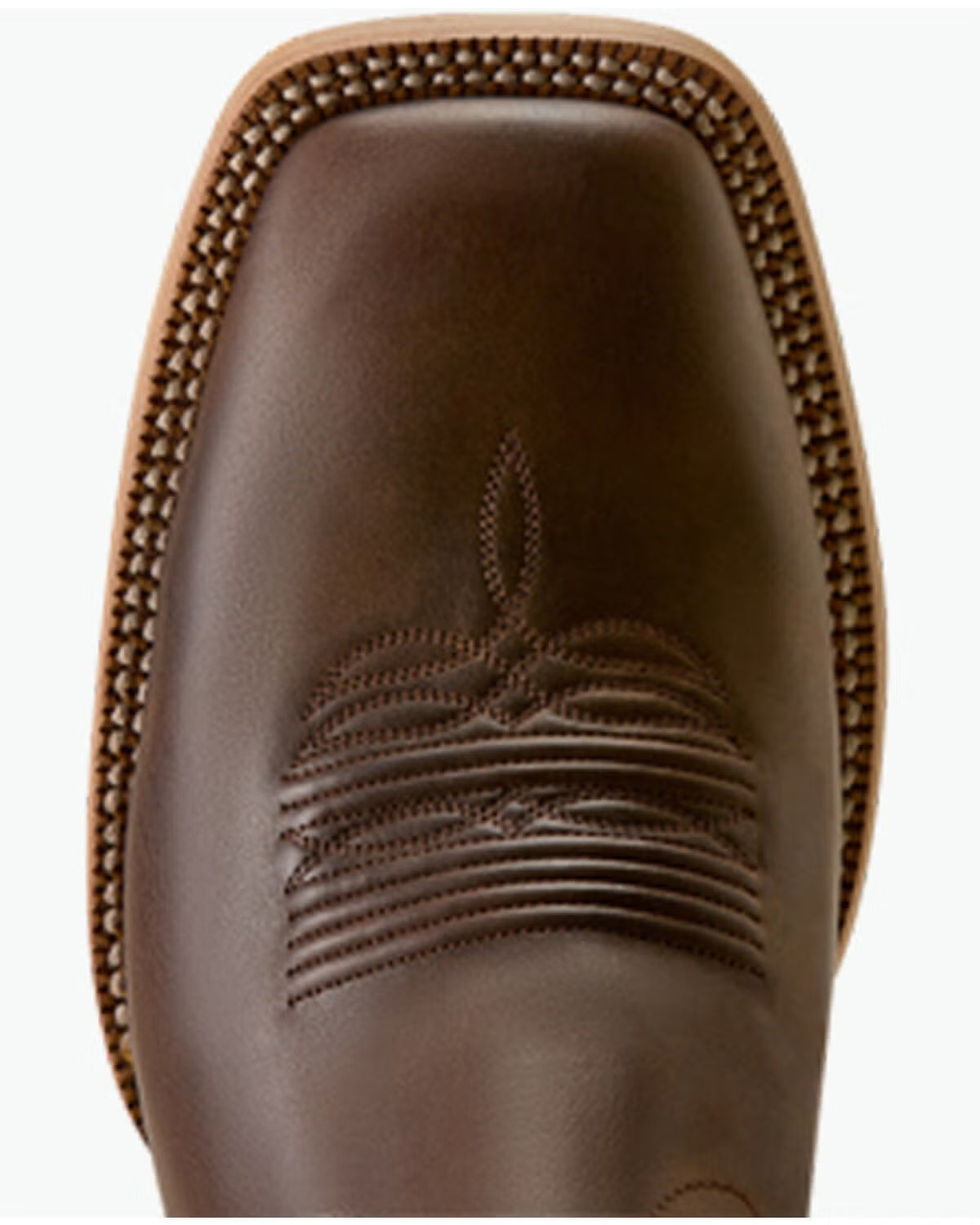 Close-up of the toe area of a brown leather cowboy boot, showing a square toe, decorative stitching, and a braided welt edge on a white background.