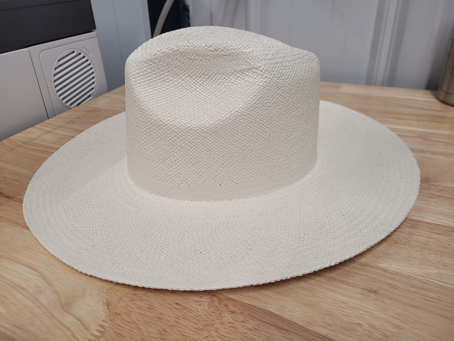 Wide brim natural straw hat with textured weave on wooden surface
