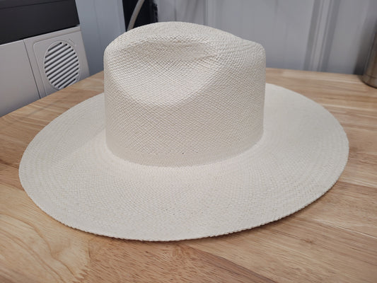 Wide brim natural straw hat with textured weave on wooden surface