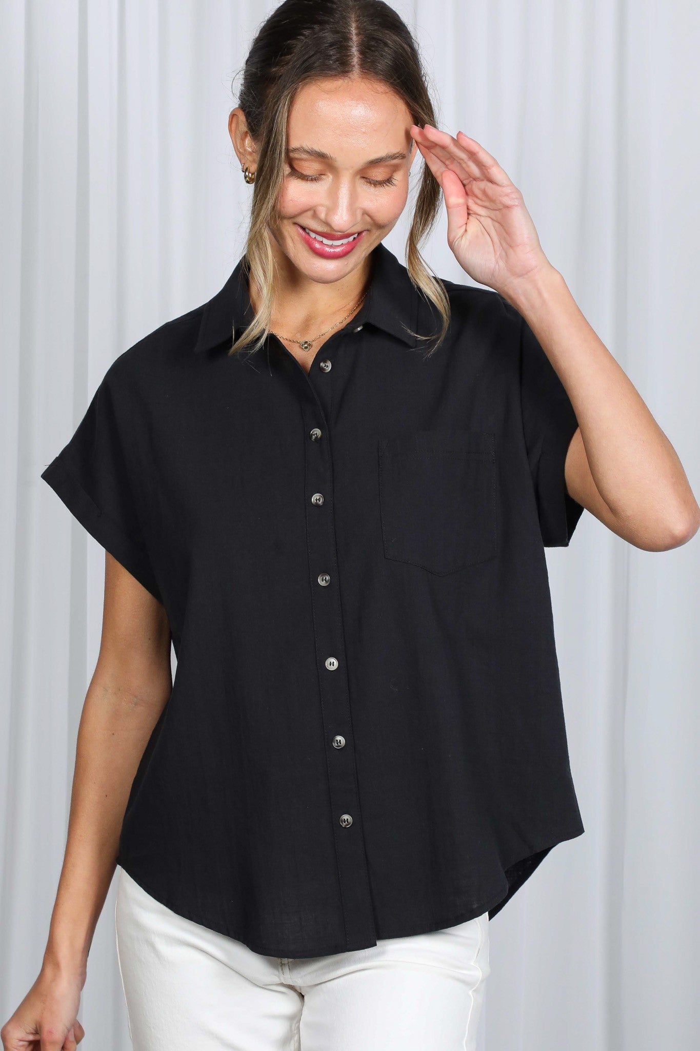 Woman wearing a black short-sleeve blouse against a white background