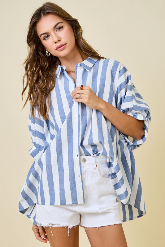Woman wearing a blue and white striped shirt with rolled-up sleeves on a beige background