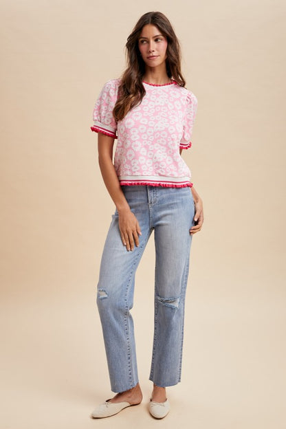 Woman wearing a pink floral top and blue jeans on a beige background