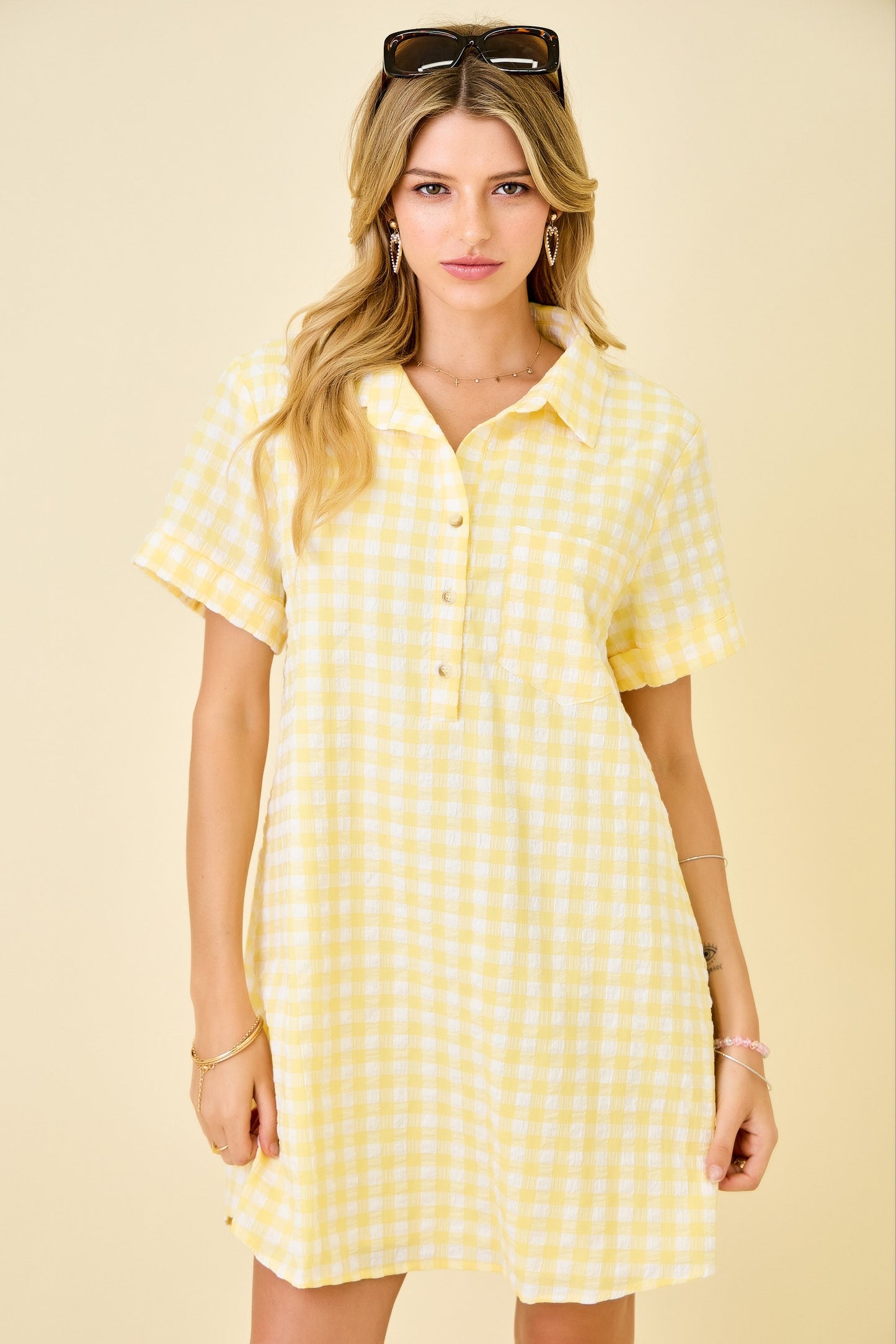 Woman wearing a yellow checkered dress against a beige background