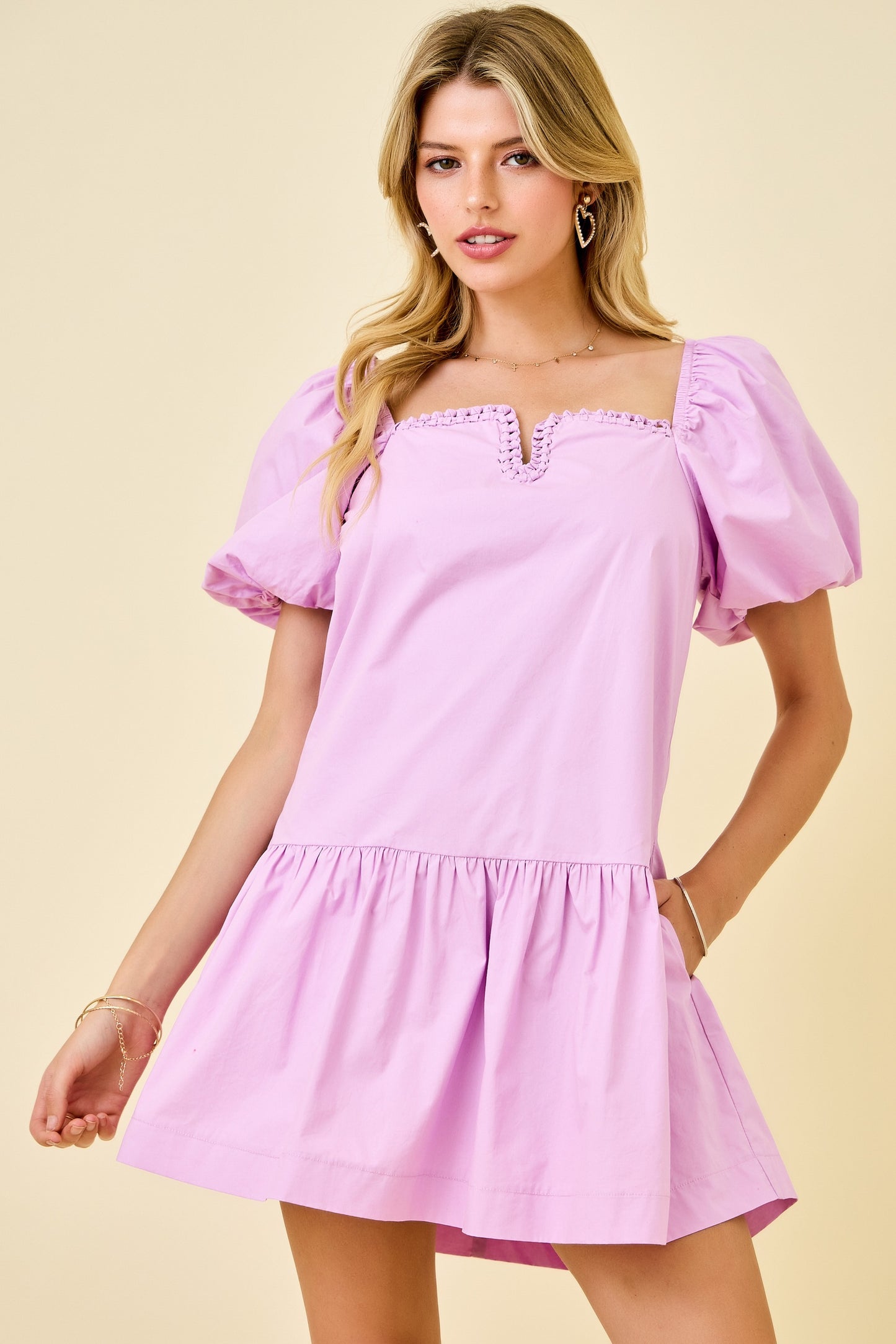 Woman wearing a pink dress with puff sleeves against a beige background