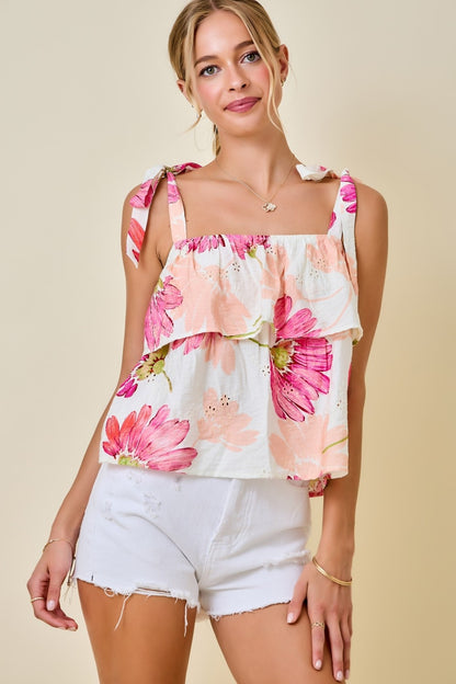 Woman wearing a floral top and white shorts on a beige background