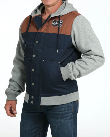 Man wearing a colorblock hooded jacket with grey sleeves and blue jeans