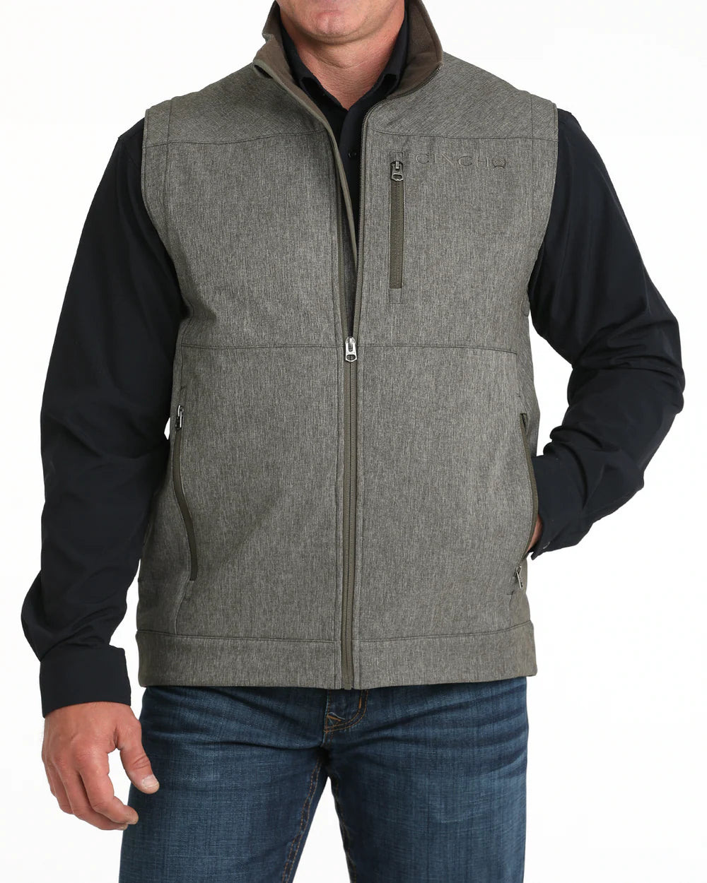 Man wearing a grey zip-up vest with chest and side pockets over a black shirt and jeans
