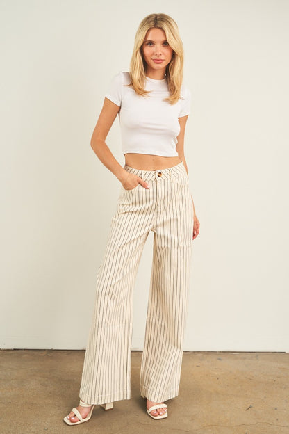 Woman wearing a white top and striped pants against a plain background