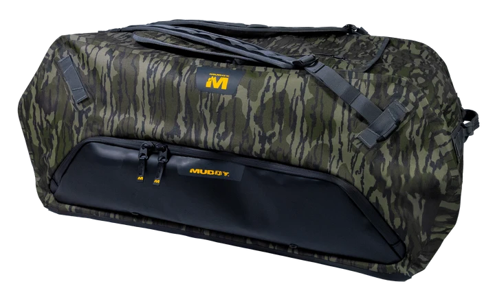 A Muddy brand duffel bag featuring a green and brown camouflage pattern with a solid black lower front pocket and black straps, shown on a plain white background.