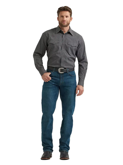 Man wearing a patterned western shirt, blue jeans, black belt, and cowboy boots