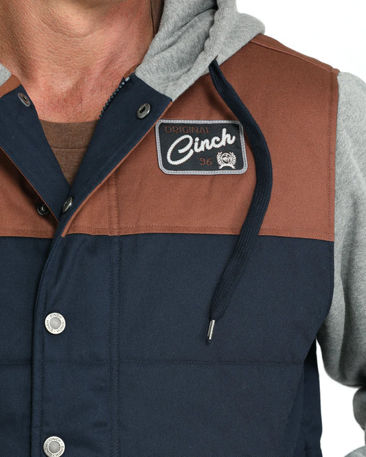 Men’s colorblock hooded vest with brown and navy panels, snap buttons, and patch logo
