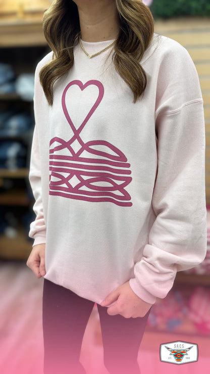 Woman wearing light pink sweatshirt with abstract heart and lines graphic design.