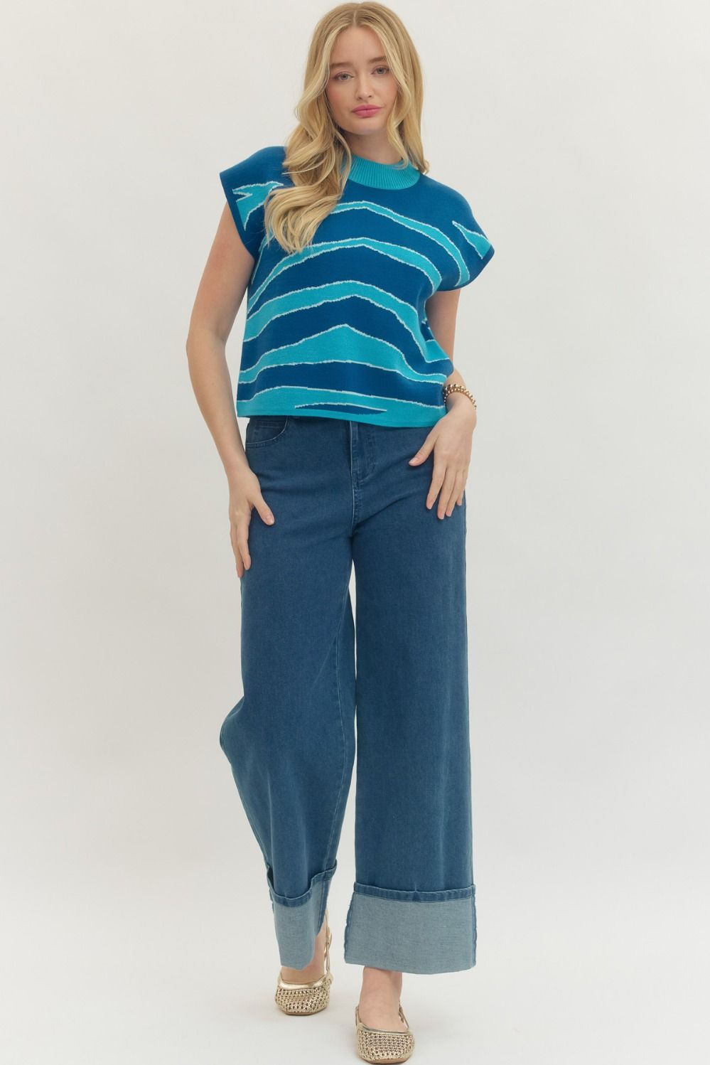 Woman wearing a blue striped top and wide-leg jeans on a white background