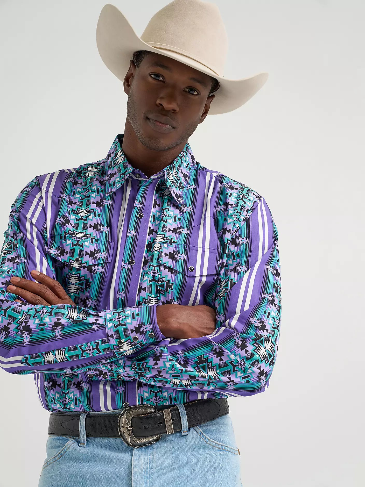 Man in cowboy hat wearing purple and turquoise patterned western shirt and belt
