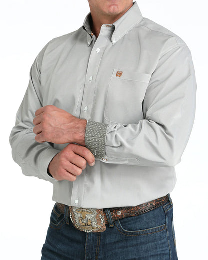 Man wearing light grey western dress shirt with patterned cuffs and blue jeans