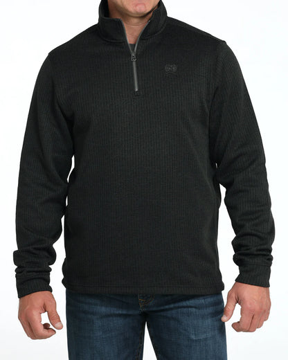 Man wearing a black quarter-zip pullover sweater and blue jeans, casual outfit