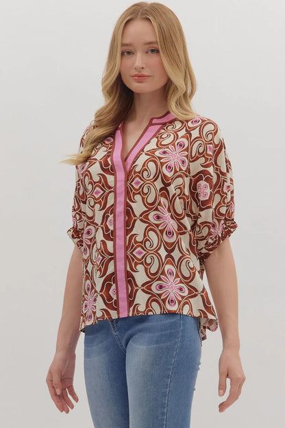 Woman wearing a patterned blouse with a pink zipper and blue jeans on a white background