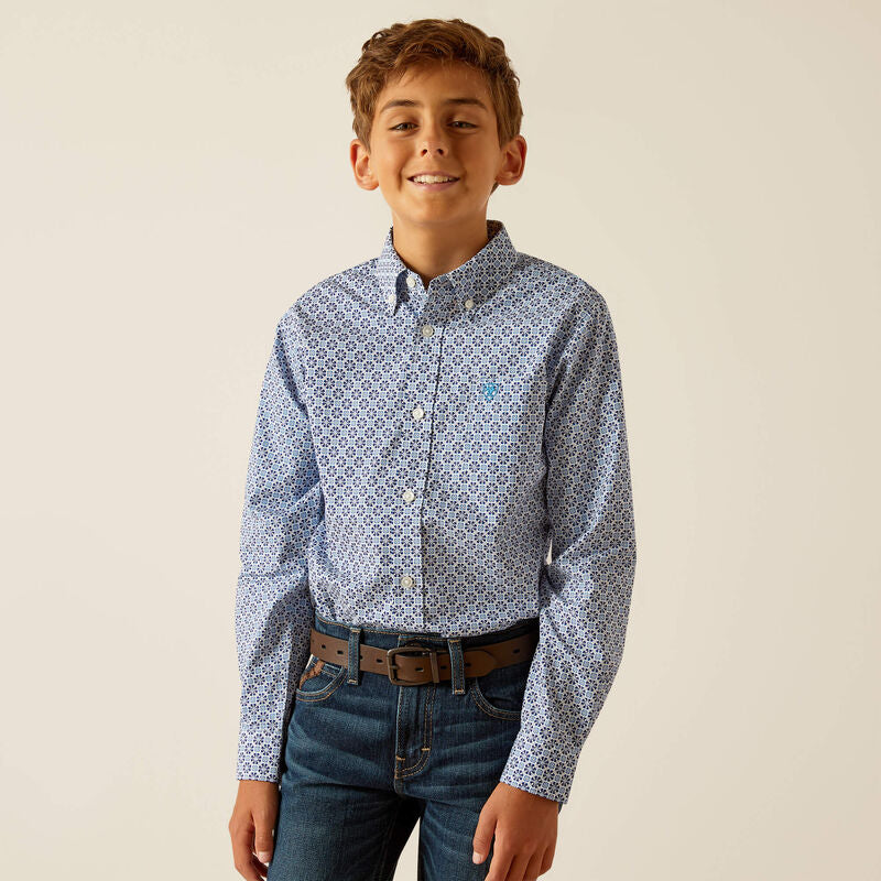 Smiling boy wearing a blue patterned button-down shirt and blue jeans with brown belt