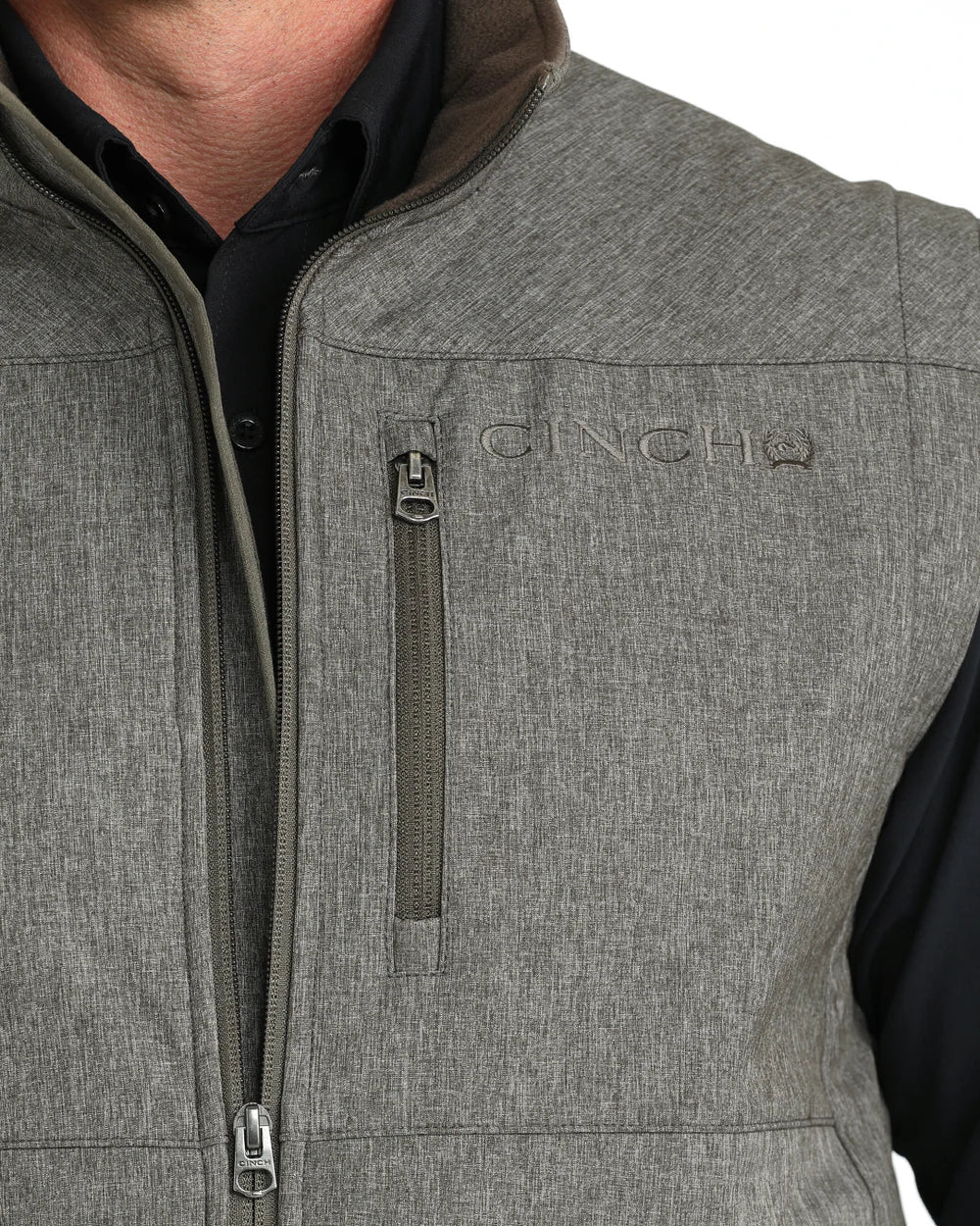 Close-up of man wearing gray zippered vest with chest pocket over black shirt
