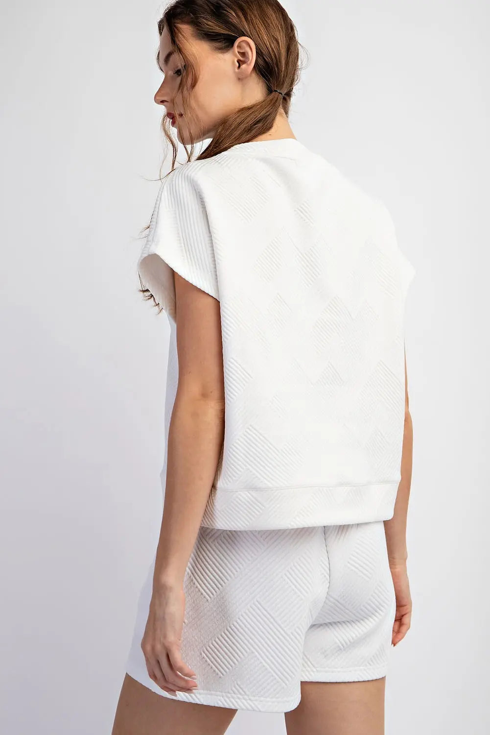 Woman wearing a white athletic outfit on a plain background