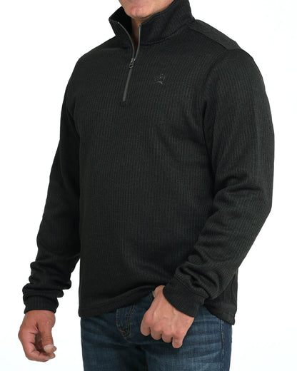 Man wearing black quarter zip pullover sweater with ribbed texture and blue jeans