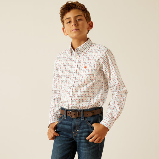 Boy wearing patterned white button-down shirt, blue jeans, and brown belt on neutral background.